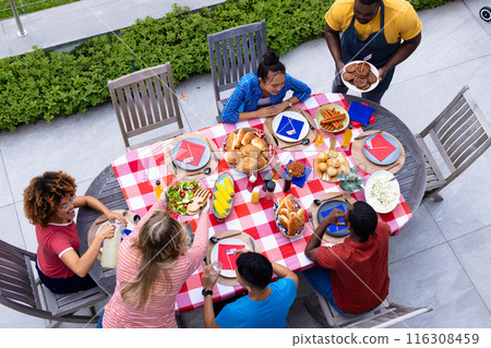 Happy diverse group of friends talking and having dinner at balcony with flags of usa Happy diverse group of friends talking and having dinner at balcony with flags of usa 116308459