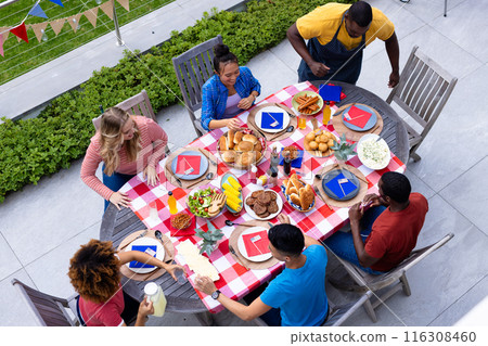 Happy diverse group of friends talking and having dinner at balcony with flags of usa 116308460