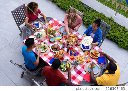 Happy diverse group of friends talking and having dinner at balcony with flags of usa Happy diverse group of friends talking and having dinner at balcony with flags of usa 116308463
