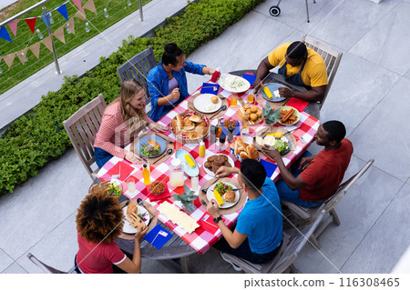 Happy diverse group of friends talking and having dinner at balcony with flags of usa Happy diverse group of friends talking and having dinner at balcony with flags of usa 116308465