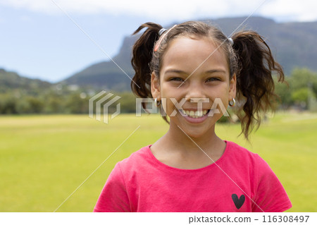 Biracial girl with a bright smile, wearing a pink shirt with a heart design, with copy space 116308497