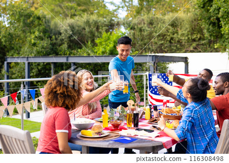 Happy diverse group of friends cheering with drinks and having dinner with flags of usa Happy diverse group of friends cheering with drinks and having dinner with flags of usa 116308498