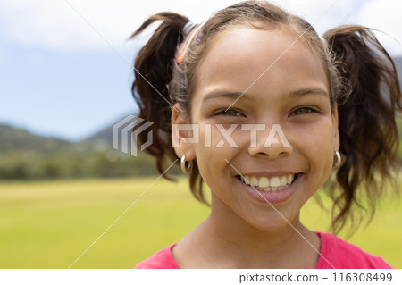 Biracial girl with a joyful smile stands outdoors 116308499