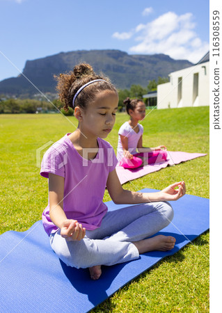 Two biracial girls are practicing yoga outdoors, one with her eyes closed in meditation Two biracial girls are practicing yoga outdoors, one with her eyes closed in meditation 116308559