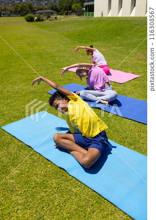 Biracial kids do yoga on colorful mats outdoors, copy space 116308567