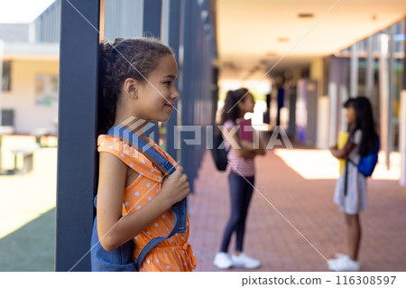 Biracial girl with a polka dot dress stands by a pillar at school, smiling, with copy space Biracial girl with a polka dot dress stands by a pillar at school, smiling, with copy space 116308597