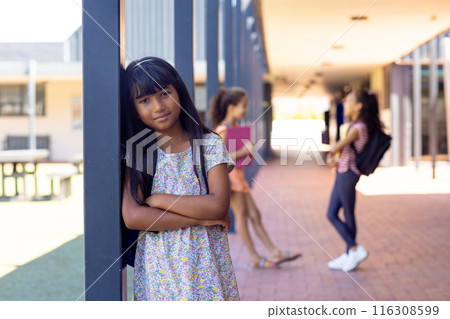 In school, three young biracial female students are standing in the hallway outdoors In school, three young biracial female students are standing in the hallway outdoors 116308599