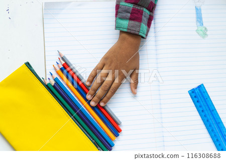 In school, in classroom, young biracial boy is selecting colored pencils 116308688