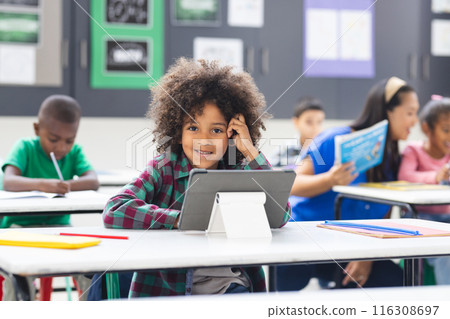 Young biracial girl with curly hair using tablet in classroom Young biracial girl with curly hair using tablet in classroom 116308697