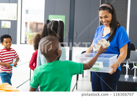 In school, middle-aged biracial teacher is showing recycling to diverse students In school, middle-aged biracial teacher is showing recycling to diverse students 116308707