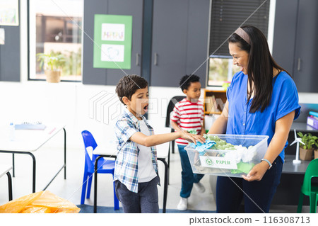 In school, in classroom, biracial female teacher and two young boys recycling 116308713