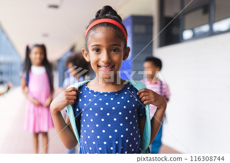 In school, young biracial girl with blue polka dot dress is smiling outdoors In school, young biracial girl with blue polka dot dress is smiling outdoors 116308744