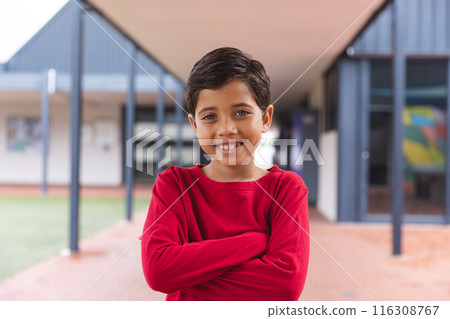 In school, young biracial male student standing with arms crossed outdoors 116308767