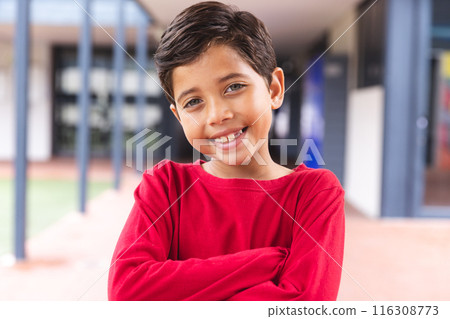 In school, outdoors, biracial young boy standing, smiling at camera 116308773