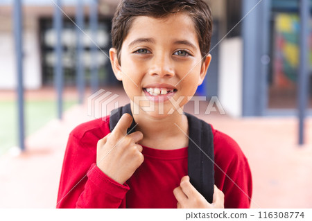 In school outdoors, biracial young boy wearing a backpack is smiling 116308774