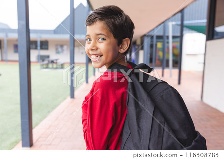 In school, young biracial male student wearing a backpack is smiling outdoors 116308783