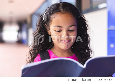In school, outdoors, biracial female student reading book 116308832