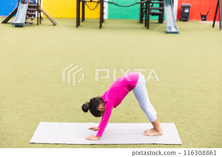In school playground outdoors, a biracial young girl wearing pink is practicing yoga In school playground outdoors, a biracial young girl wearing pink is practicing yoga 116308861