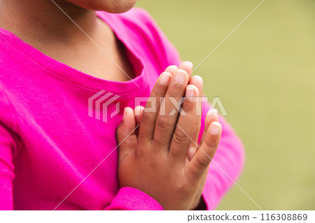 At school, young biracial girl in a bright pink top is praying outdoors and doing yoga At school, young biracial girl in a bright pink top is praying outdoors and doing yoga 116308869