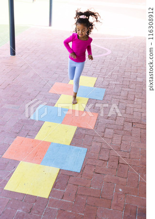 In school, young biracial girl is playing hopscotch outdoors with copy space In school, young biracial girl is playing hopscotch outdoors with copy space 116308912