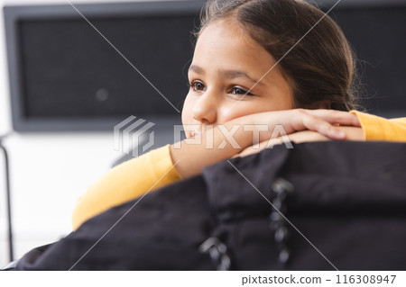 In school, young biracial female student resting chin on hands, looking away in the classroom 116308947