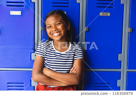 In school, young biracial female student is standing outdoors, arms crossed, smiling 116308979