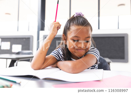 In school, young biracial girl with light brown skin is thinking in the classroom 116308997