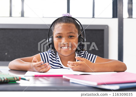 In school, young biracial girl wearing headphones is learning in the classroom In school, young biracial girl wearing headphones is learning in the classroom 116309035