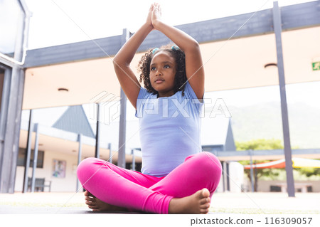Biracial girl practices yoga outdoors at school Biracial girl practices yoga outdoors at school 116309057