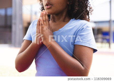 Biracial girl practices yoga outdoors at school 116309069