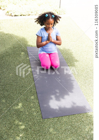 Biracial girl practices yoga outdoors at school Biracial girl practices yoga outdoors at school 116309085