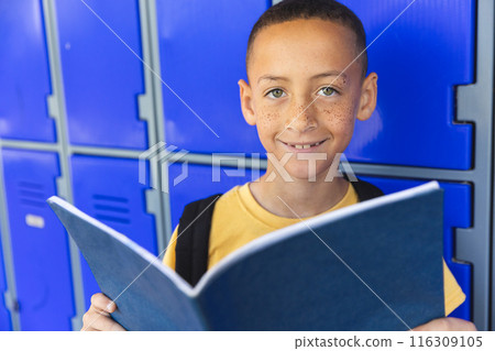 Biracial boy smiles holding a book in school 116309105