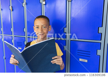 Biracial boy stands in front of school lockers, with copy space 116309106