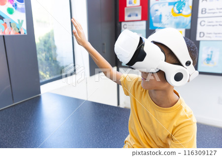 In a school, a biracial boy explores virtual reality using a headset in the classroom In a school, a biracial boy explores virtual reality using a headset in the classroom 116309127
