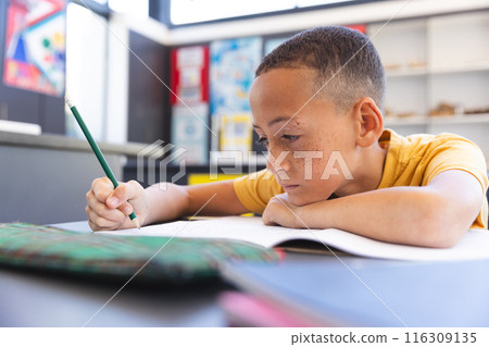 Biracial boy focuses on schoolwork at school 116309135