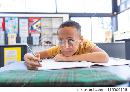 Biracial boy focuses on his schoolwork at school 116309136