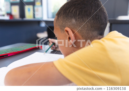 In a school setting, in a classroom, a biracial boy is focused on his work In a school setting, in a classroom, a biracial boy is focused on his work 116309138
