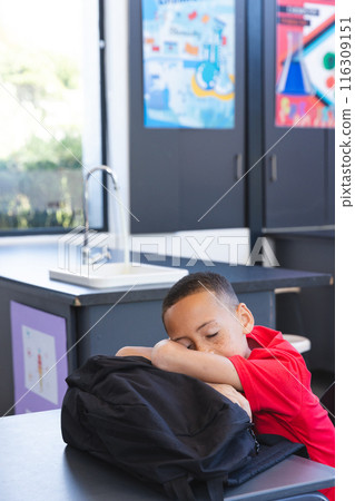 Biracial boy rests his head on a backpack at school Biracial boy rests his head on a backpack at school 116309151