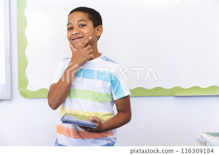 Biracial boy holds a tablet in a classroom setting in school Biracial boy holds a tablet in a classroom setting in school 116309184