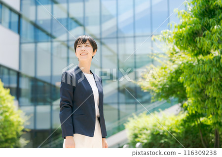 一位穿著西裝的女士站在辦公大樓前 一位穿著西裝的女士站在辦公大樓前 116309238