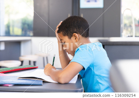 Biracial boy focused on schoolwork in the classroom at school 116309254