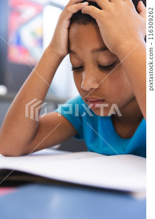 Biracial boy studies intently in the classroom at school 116309262