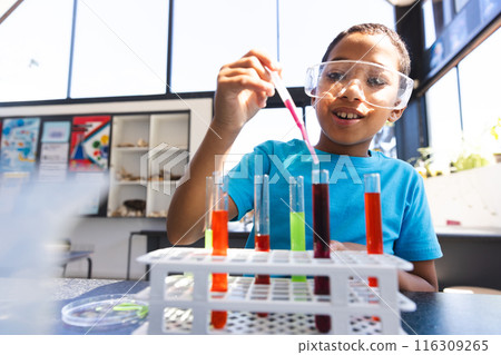 Biracial boy conducts an experiment in a science classroom at school Biracial boy conducts an experiment in a science classroom at school 116309265