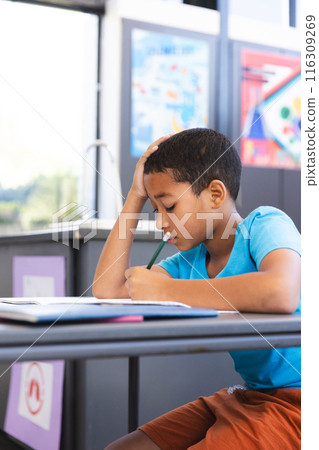 Biracial boy focused on schoolwork at school 116309269