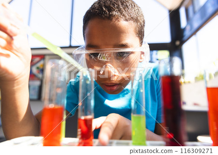 Biracial boy examines test tubes in a school lab 116309271
