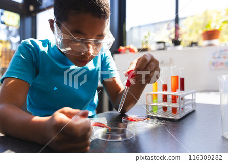 Biracial boy engages in a science experiment at school in the classroom 116309282