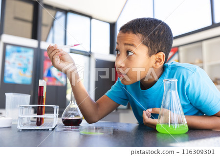 Biracial boy engaged in a science experiment at school in the classroom Biracial boy engaged in a science experiment at school in the classroom 116309301