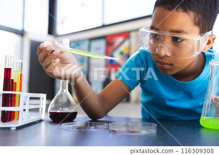 Biracial boy engaged in a science experiment at school in the classroom 116309308