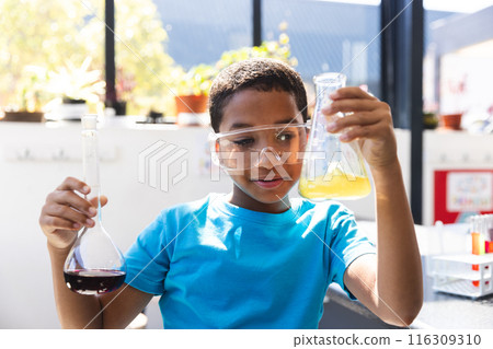 Biracial boy examines science experiment at school in the classroom Biracial boy examines science experiment at school in the classroom 116309310
