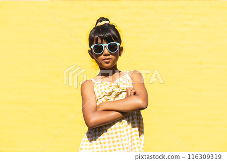 Biracial girl wearing sunglasses and a sundress poses confidently outdoors Biracial girl wearing sunglasses and a sundress poses confidently outdoors 116309319